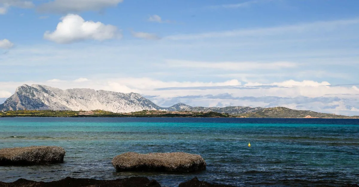 Impresionante vista de la playa de San Teodoro con aguas turquesas y un fondo montañoso.