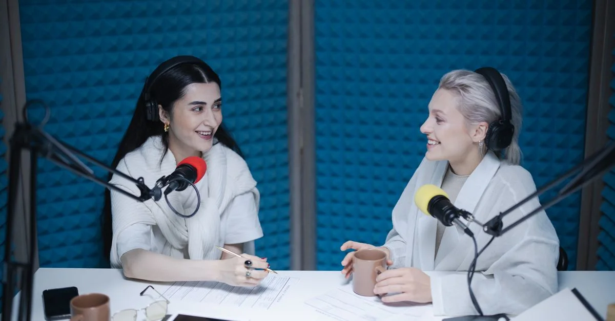 Dos mujeres participando en una animada discusión de podcast dentro de un entorno de estudio profesional.