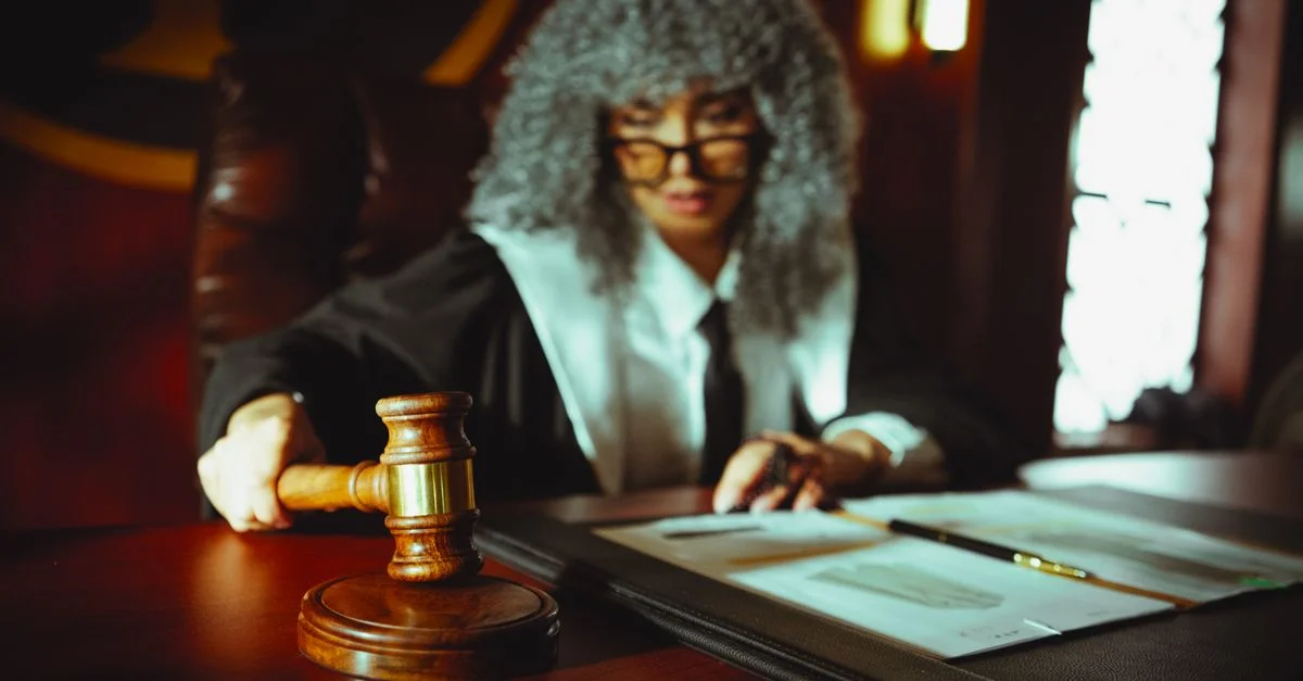 Jueza femenina en un entorno de tribunal, enfocándose en documentos legales con un mazo.