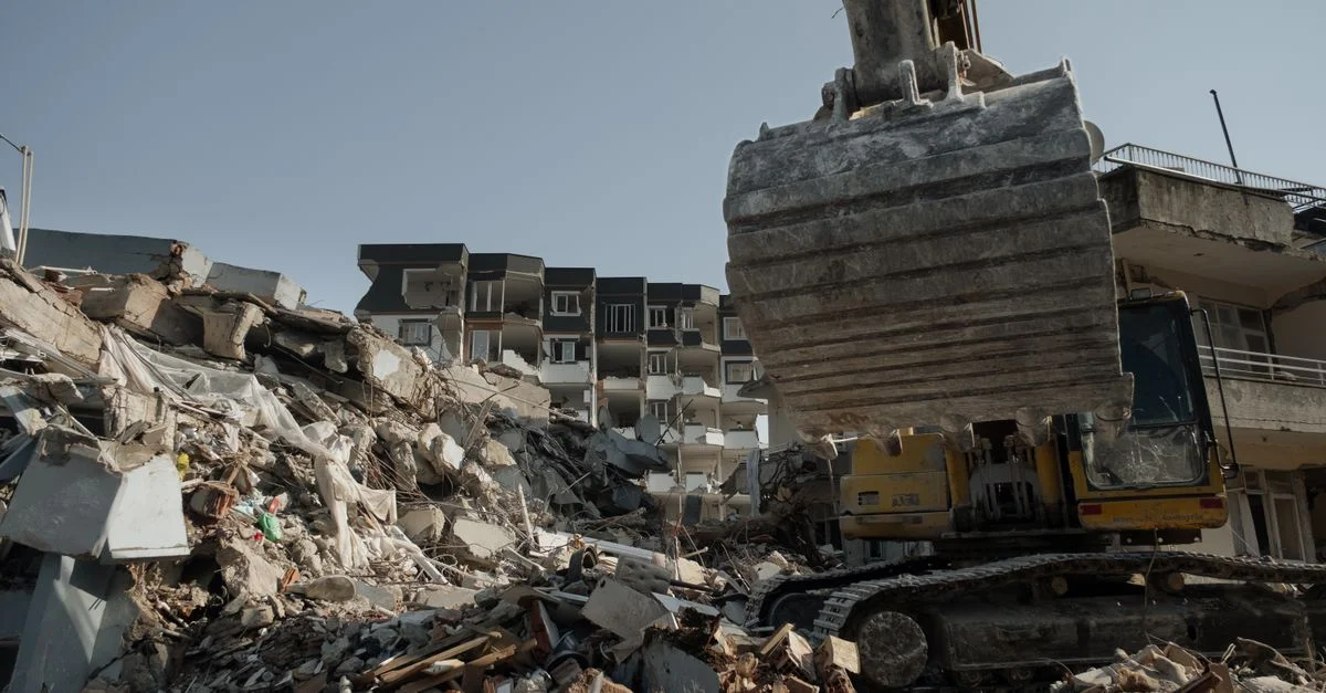 Poderosa excavadora limpiando escombros del terremoto entre las ruinas de edificios en Antakya, Turquía.
