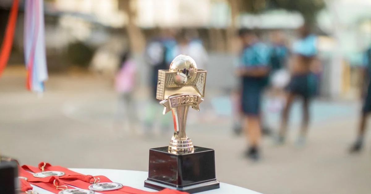 Gros plan d'un trophée de football poli avec des médailles lors d'une cérémonie de remise de prix de sports en plein air.