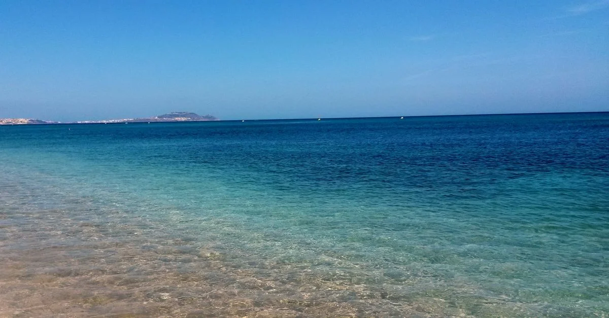 Hermosa y tranquila playa en Marruecos con agua turquesa y horizonte claro, perfecta para unas relajantes vacaciones de verano.
