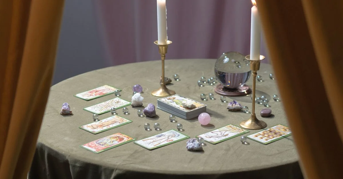 Une table de lecture de tarot magique garnie de bougies allumées, de cristaux et de cartes de tarot suggérant le mysticisme.